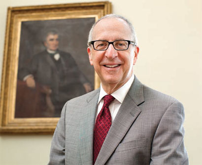 President Skorton poses for a photo in front of a painted portrait